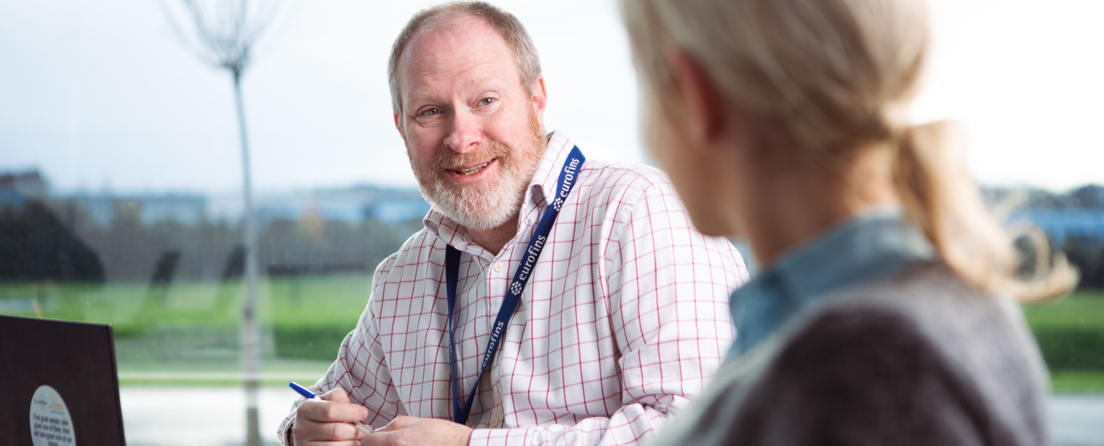 A man in the foreground with a shirt smiling at a woman in front of him